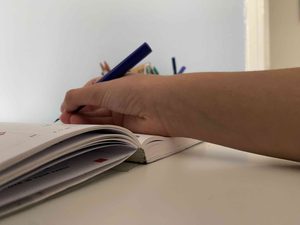 Un jeune écrit dans son agenda, mais l'épaisseur de ce dernier casse son poignet.